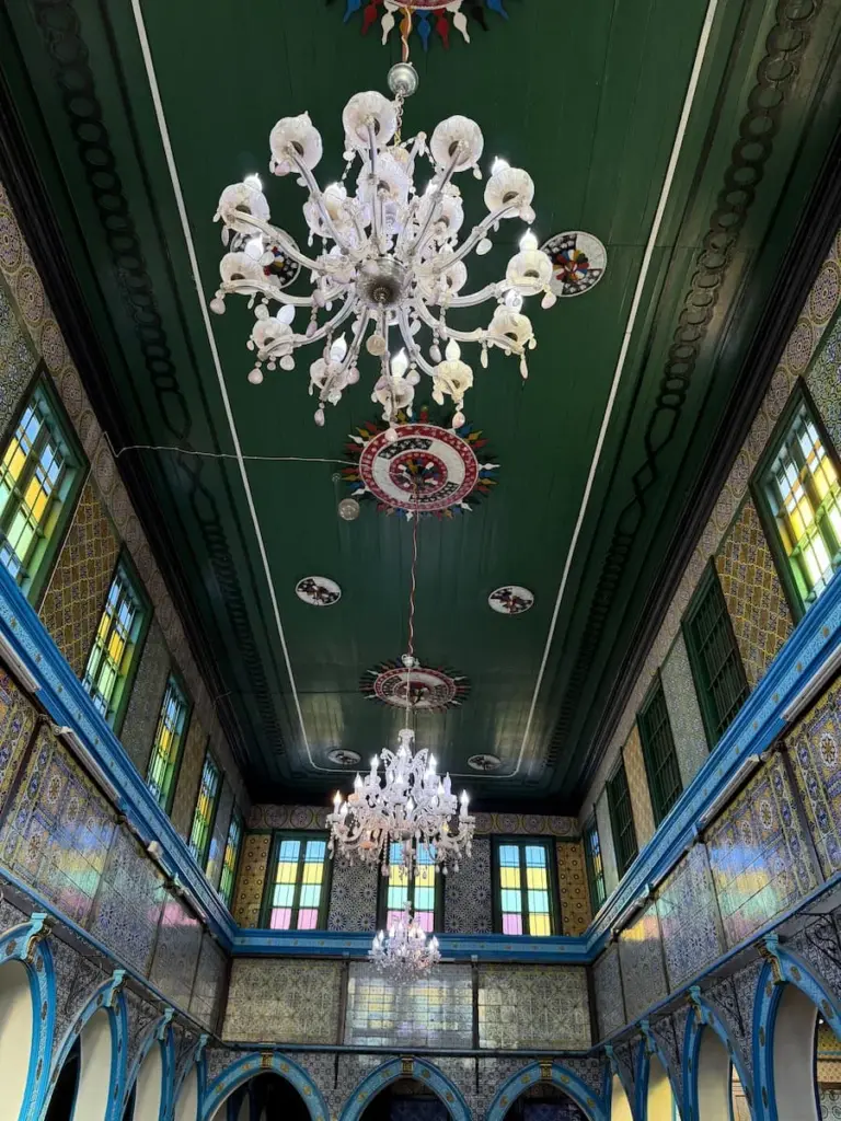 Chandelier at El Ghriba Synagogue, Djerba on the green ceiling surrounded by colourful glass windowns