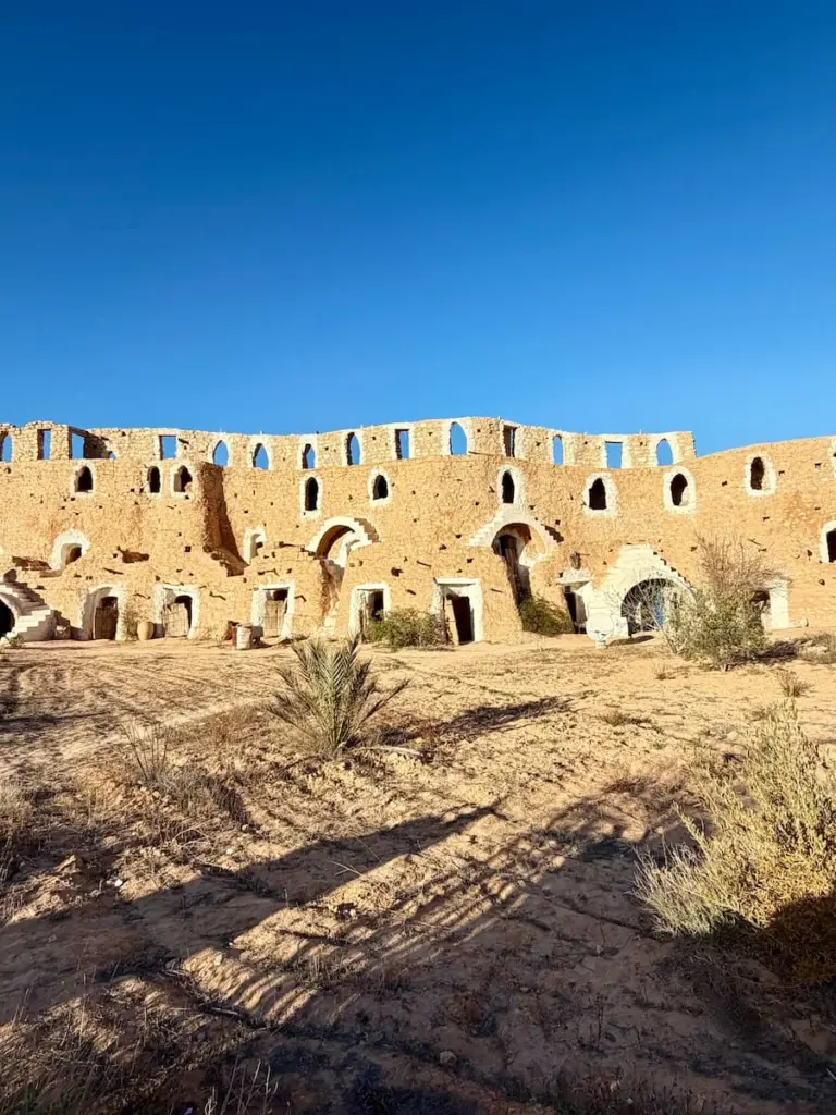 A row of restored troglodyte houses in Matmata, Tunisia with stairs and white fascia work around the windows and doors.