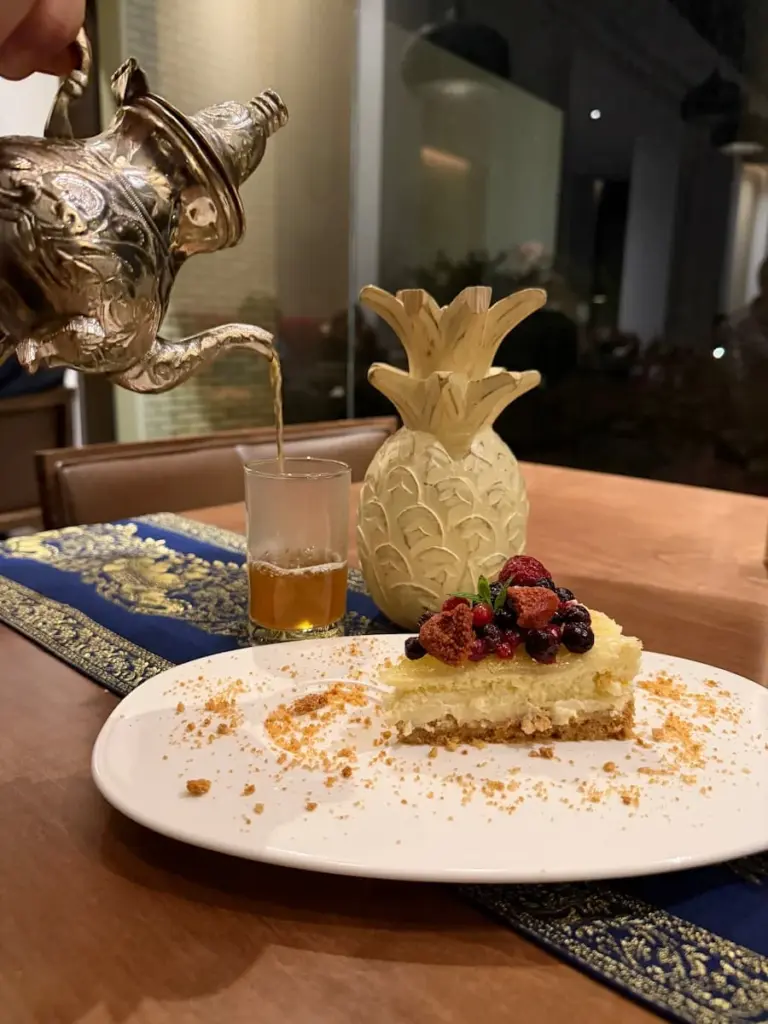 Mekong restaurant at the Mora, Tozeur desert, Tunisia. A slice of berry cheesecake on a white plate with a pineapple centre piece on the table