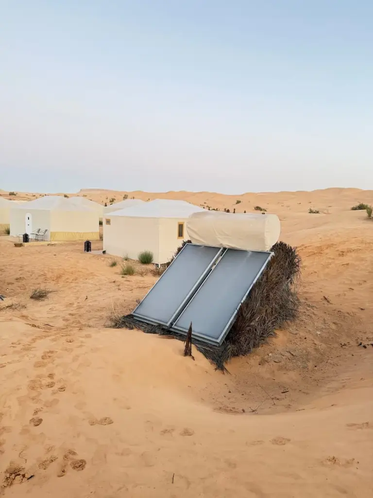 Solar panels at Camp Abdelmoula on the sand dunes with white tents in the background