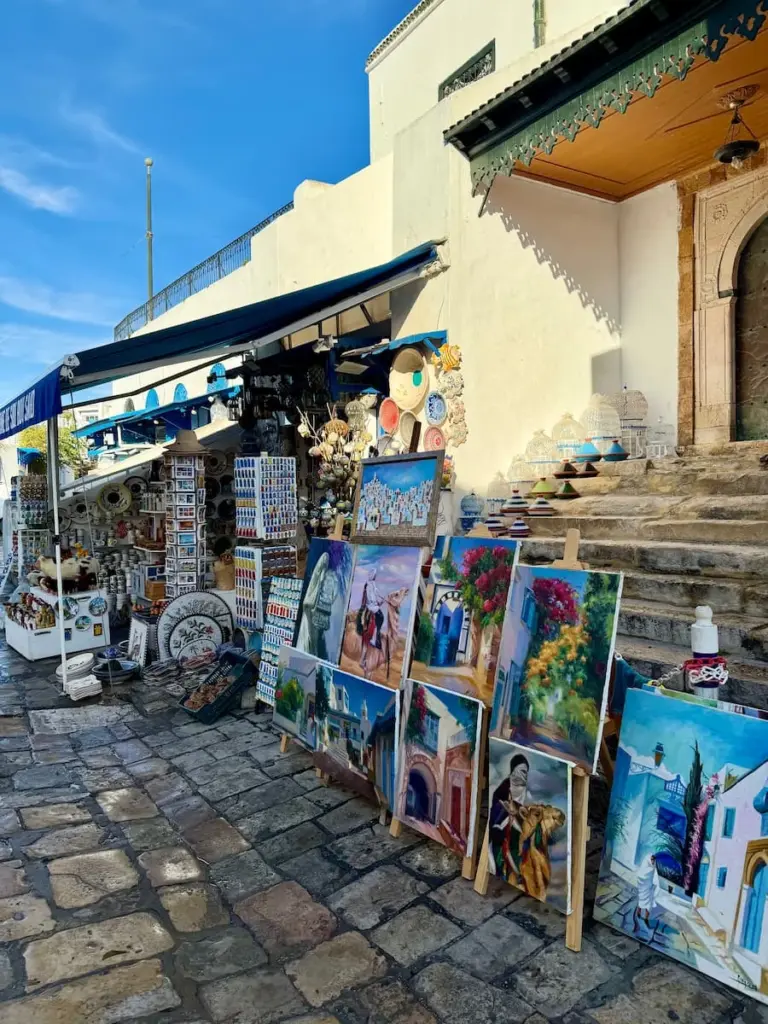 Watercolour stall on cobbled stoned main street in Sidi Bou Said, Tunisia. The water colours are laid out against a white wall.